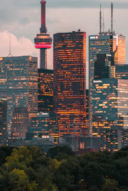 A refined aerial view of Toronto’s skyline at dusk, with the CN Tower illuminated in gold.