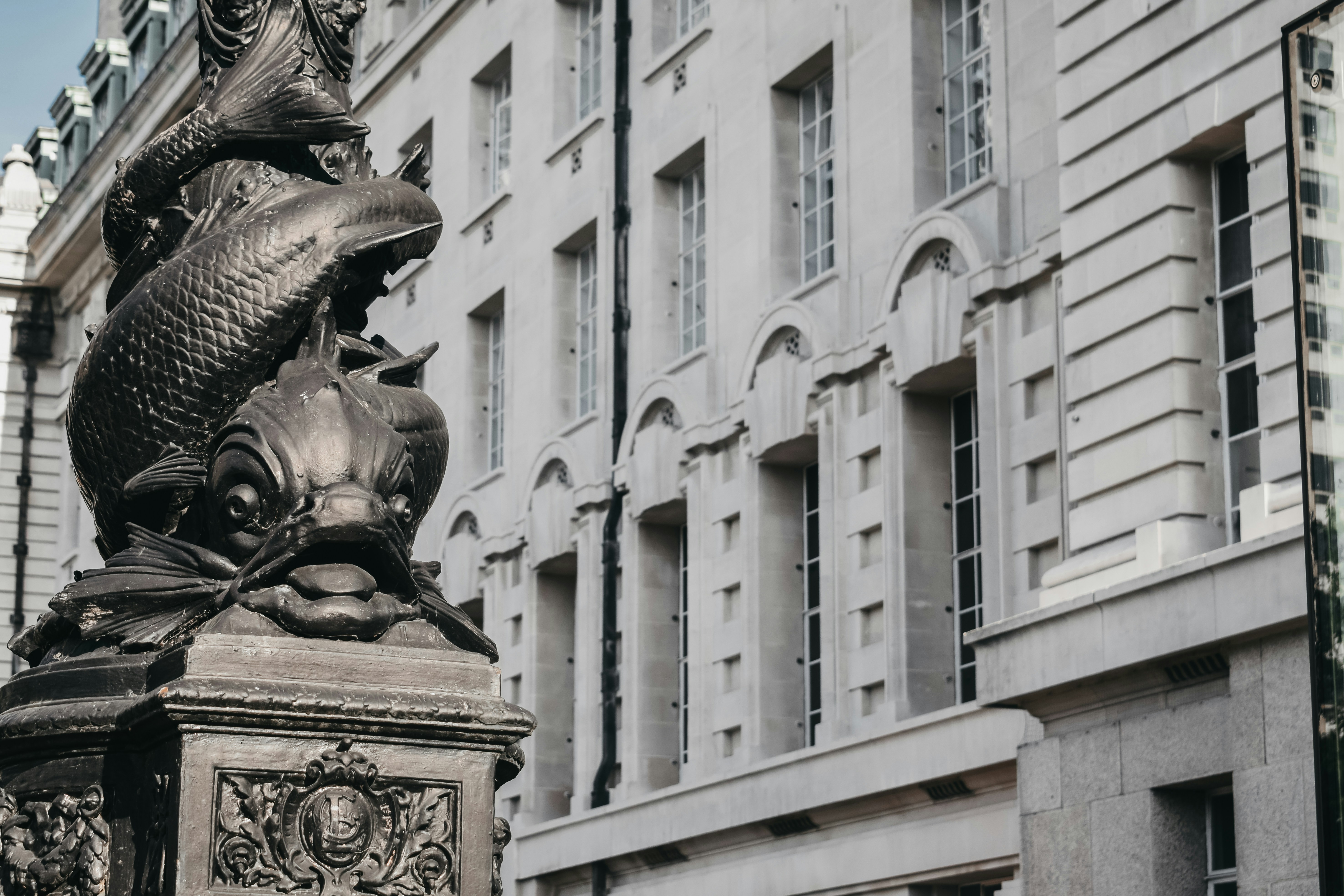 a statue of a fish on a pedestal in front of a building