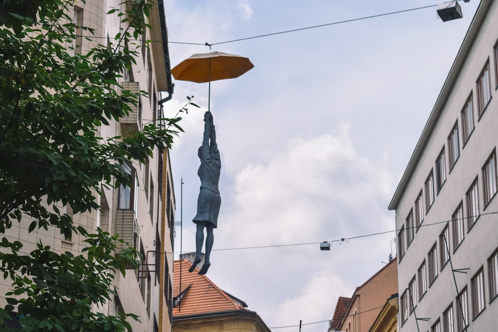 human statue hanging from an umbrella
