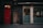 A narrow urban street scene features a striking red door with a windowpane that displays the address 36-38 Glasshouse St. Adjacent to the door is a small entrance labeled as a fire exit, marked by graffiti. Large glass windows with patterned designs suggest a modern interior space, where a few people can be seen seated indoors.