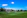 Students playing cricket on the lush green school grounds under a bright blue sky.