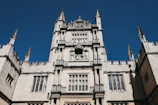 Elegant stone castle facade with intricate European architectural details under a clear blue sky.