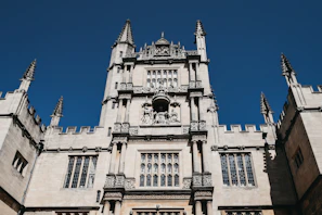 Elegant stone castle facade with intricate European architectural details under a clear blue sky.