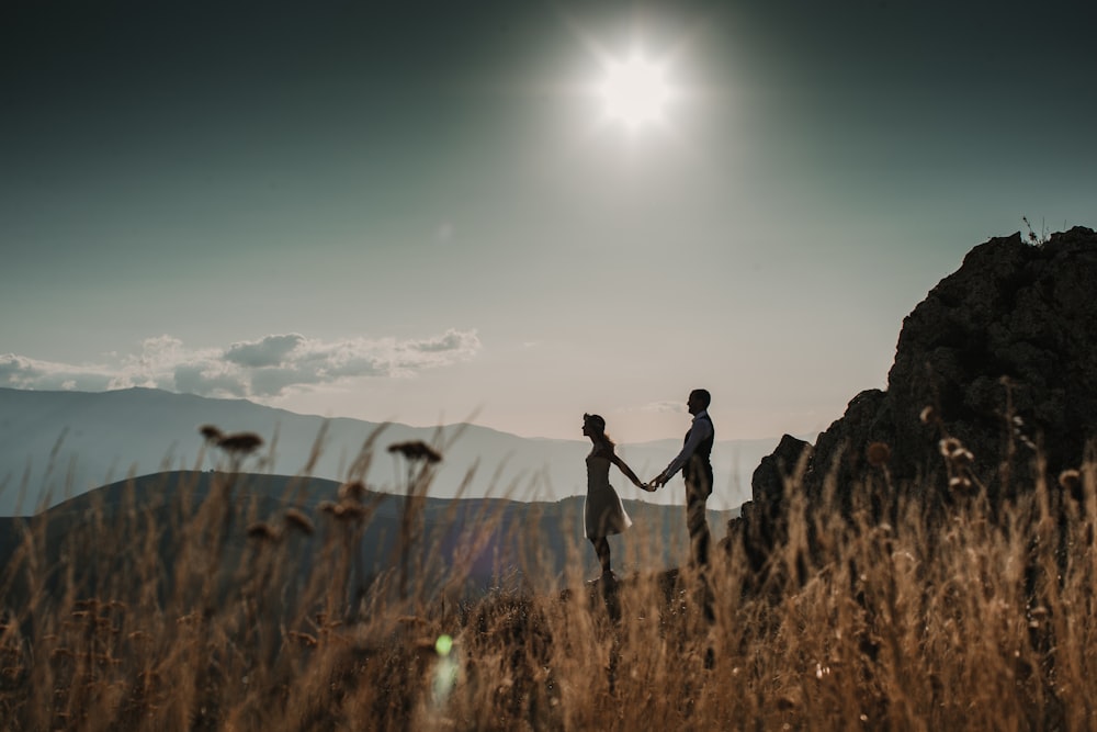 um casal de mãos dadas enquanto está no topo de uma montanha