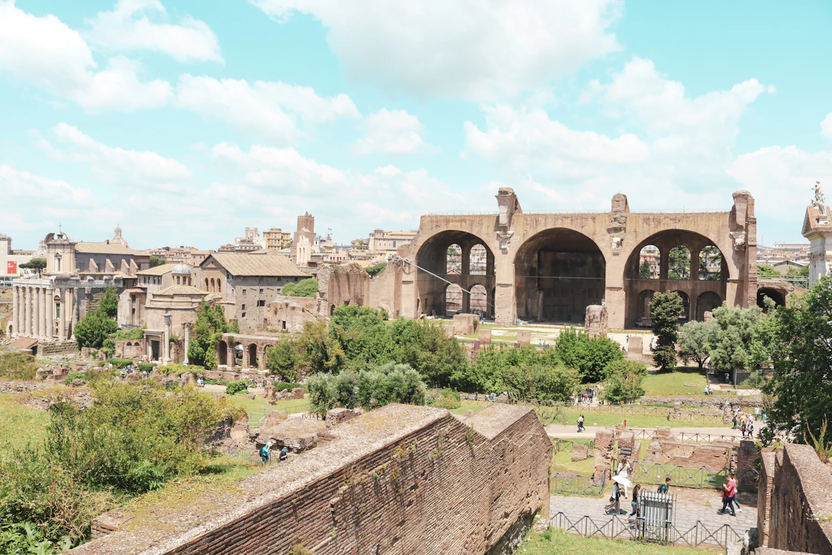 The Roman Forum ruins at golden hour with ancient columns and arches stretching toward the Colosseum in Rome Italy