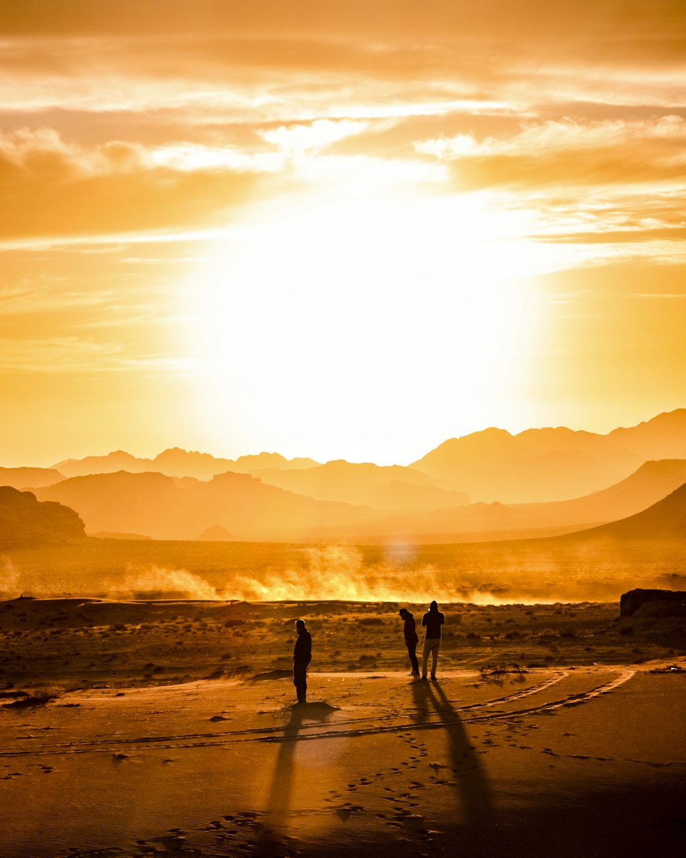 three persons at the sand dunes during golden hour