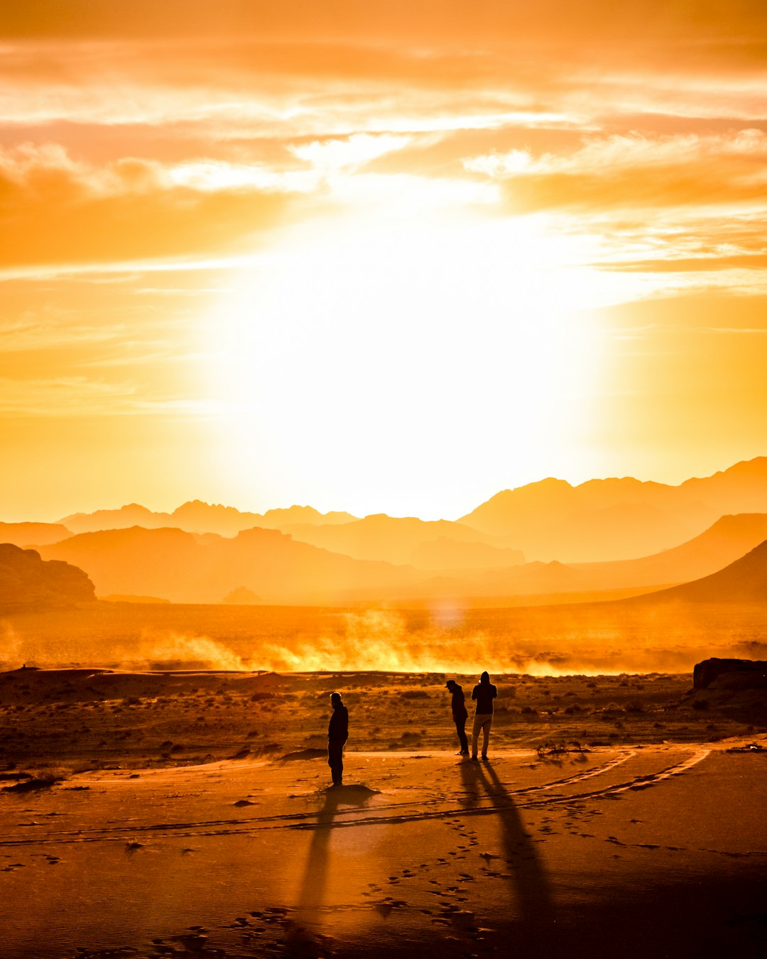 three persons at the sand dunes during golden hour