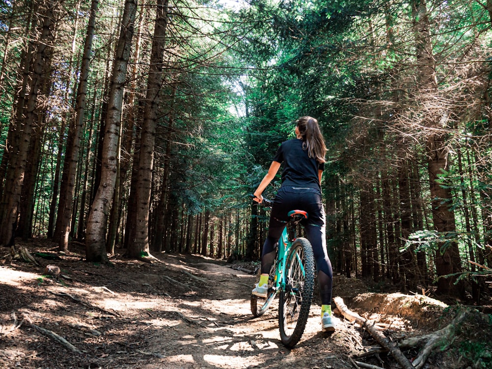 Mulher que anda na bicicleta azul dentro da floresta