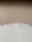 A textured wall with a mix of paint colors, featuring an upper section in beige and a lower section in off-white. Visible brush strokes and uneven painting create a rustic and unfinished look.
