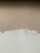 A textured wall with a mix of paint colors, featuring an upper section in beige and a lower section in off-white. Visible brush strokes and uneven painting create a rustic and unfinished look.