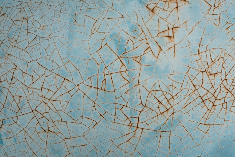 a close up of a blue wall with cracks in it