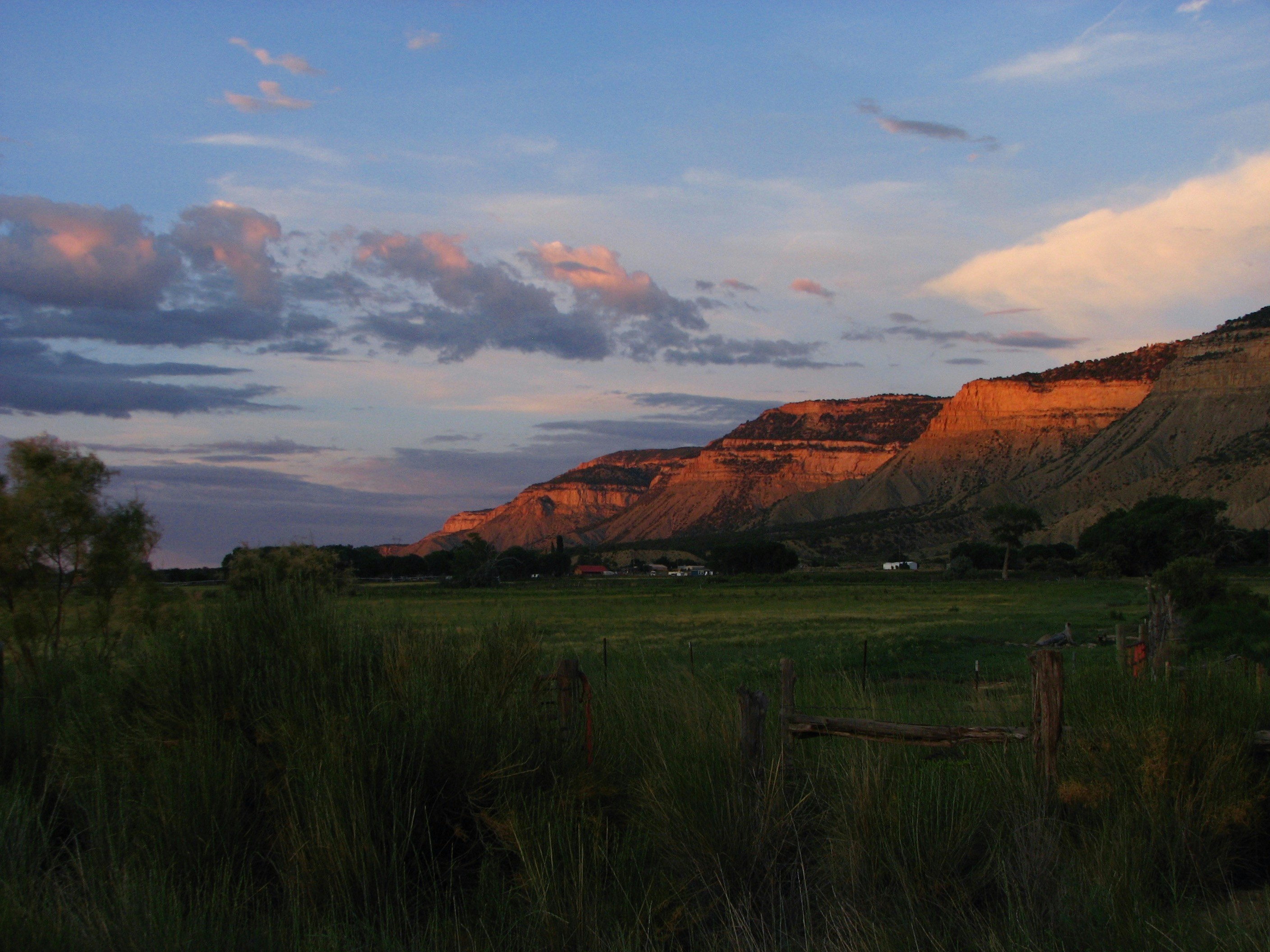 aerial photography of green field viewing mountain under blue and white skies during daytime