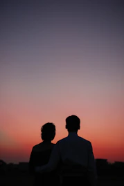 man and woman standing and looking sunset