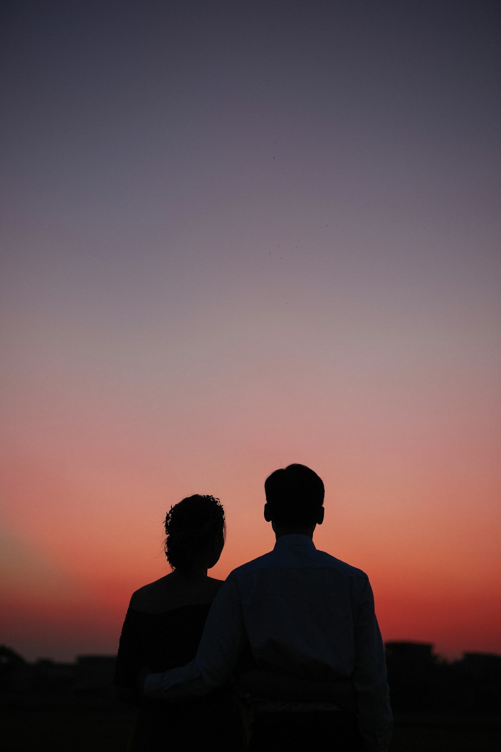 man and woman standing and looking sunset