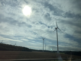 Wind turbines standing tall against a cloudy sky on the rugged Vlašić plateau.