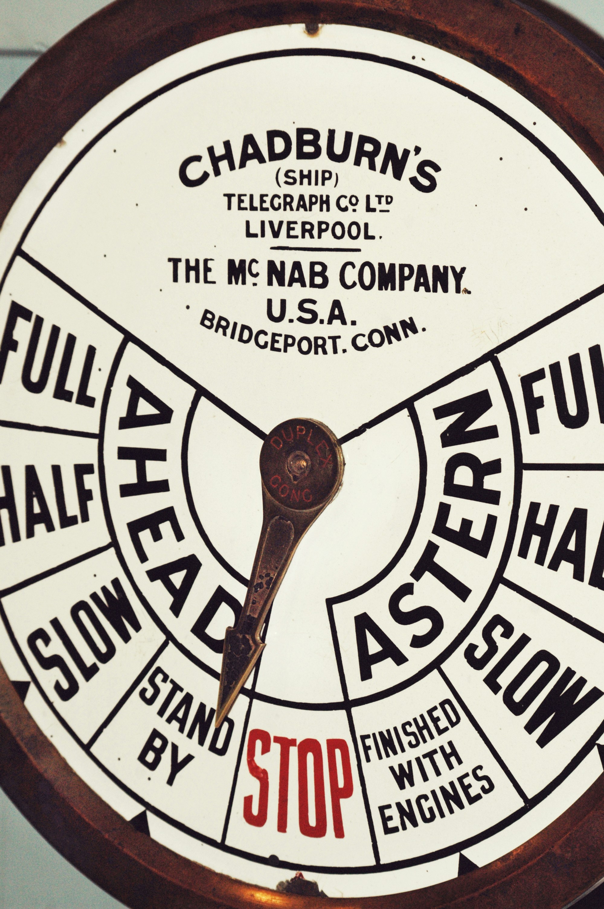 Detail shot of a ship or vessel's propulsion system, filled with large text print and words giving speed readouts. Patina covers the metal round dial and needle.