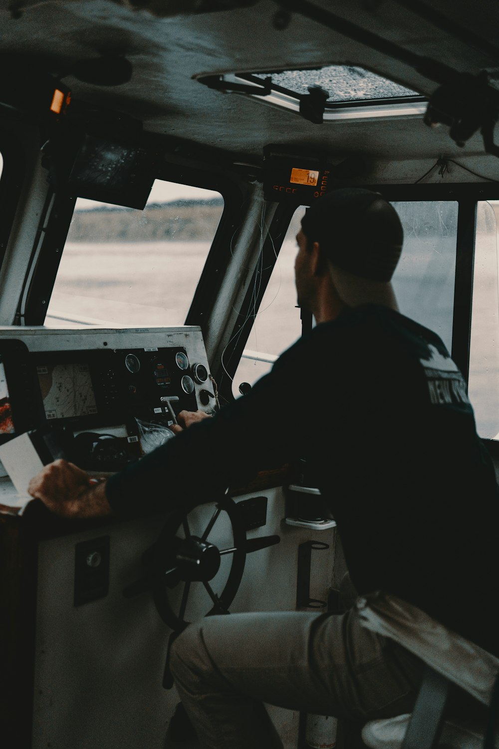 man sitting in front of boat steering wheel