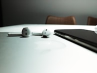 A pair of wireless earphones with a matte finish displayed against a soft fabric background.