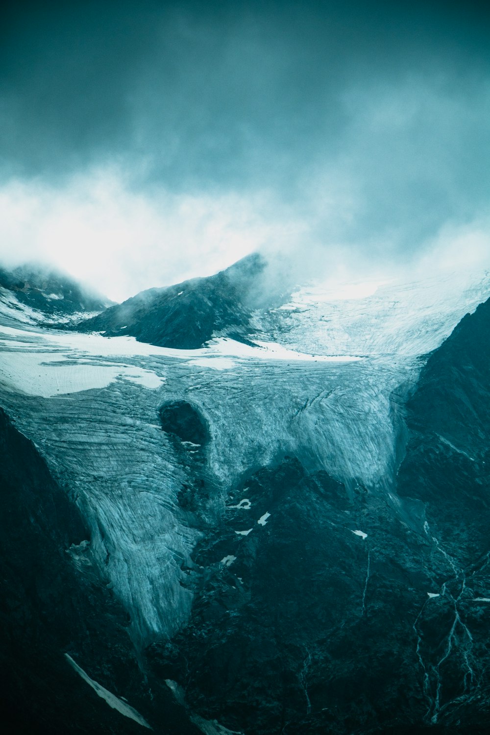 a mountain covered in snow under a cloudy sky