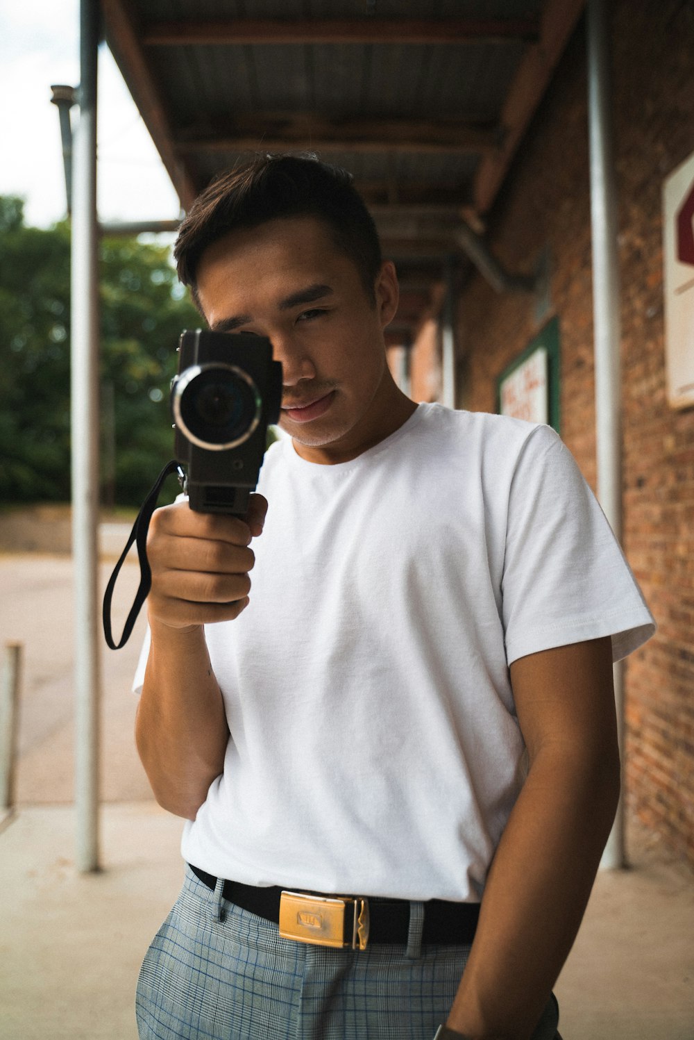 man wearing white crew-neck shirt holding video camera