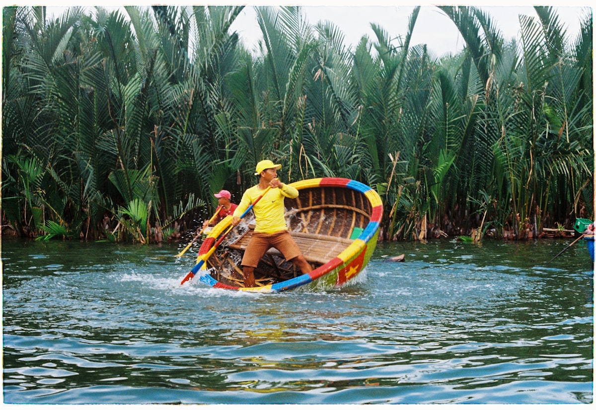 Hoi An Thu Bon River — two men in a traditional round basket boat among coconut palms near the resort belt