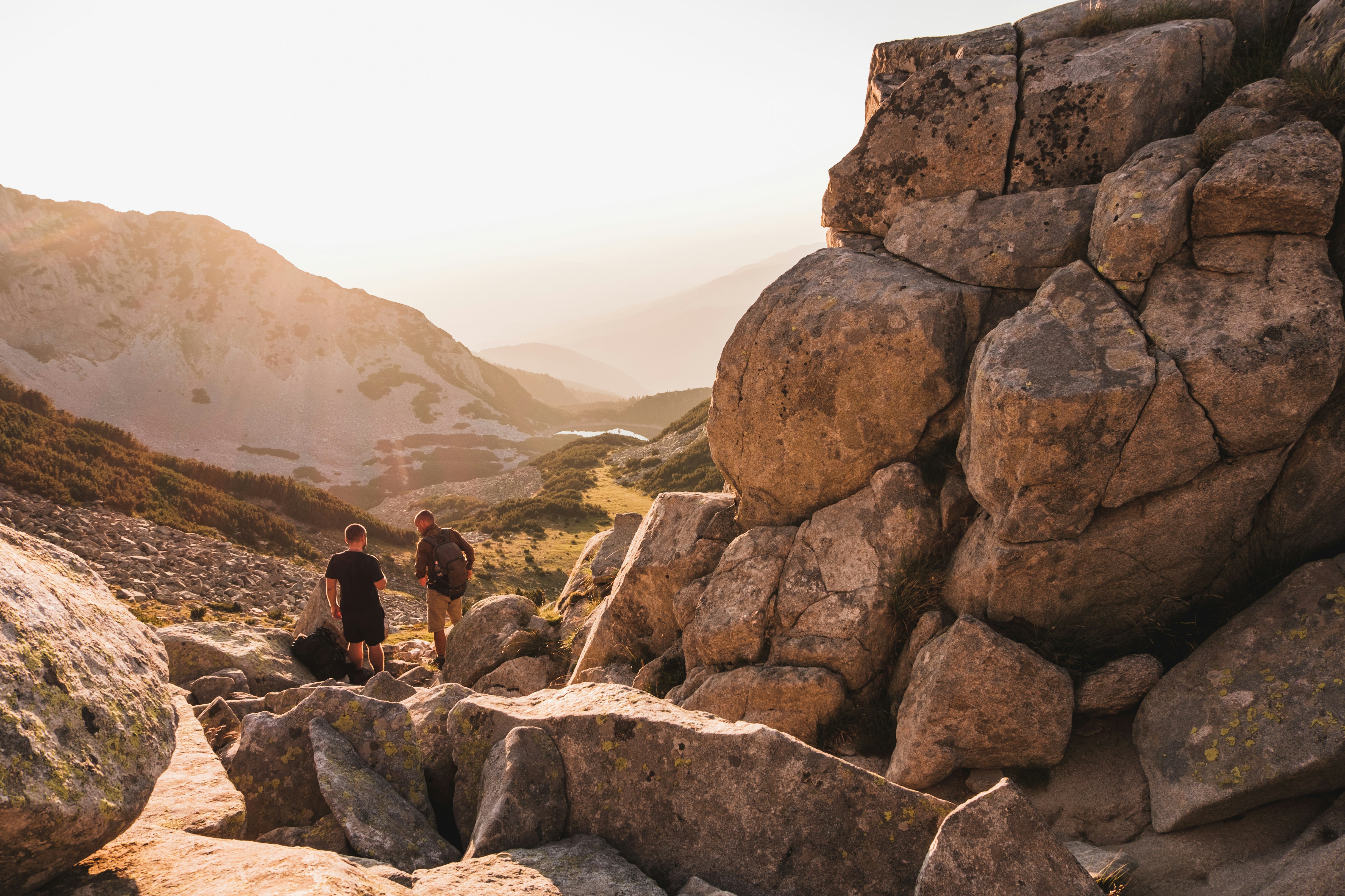 2 men standing besides chunk of rocks