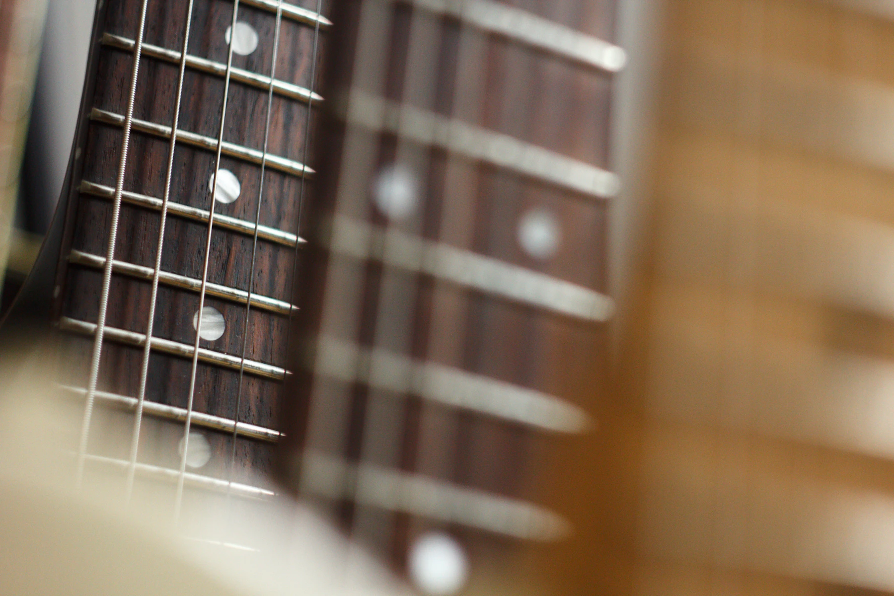 A close-up of strings crossing the frets on a guitar fretboard