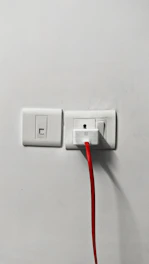 Close-up of an electrician installing a power outlet with tools.