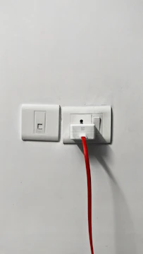 Close-up of an electrician installing a power outlet with tools.