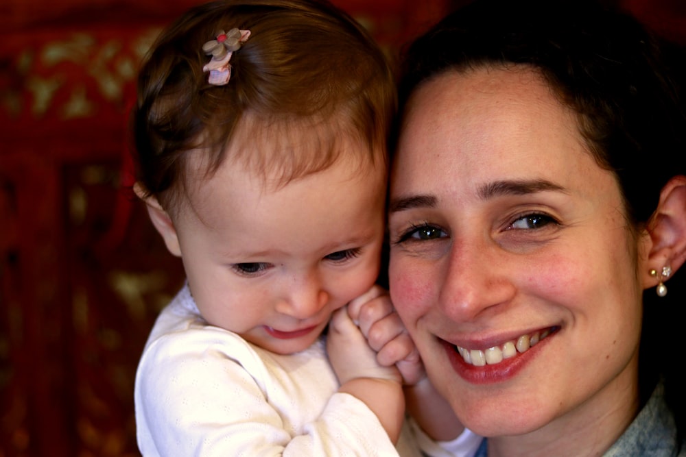 smiling woman in blue top cuddling baby