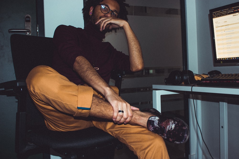 man wearing brown pants sitting in front of computer