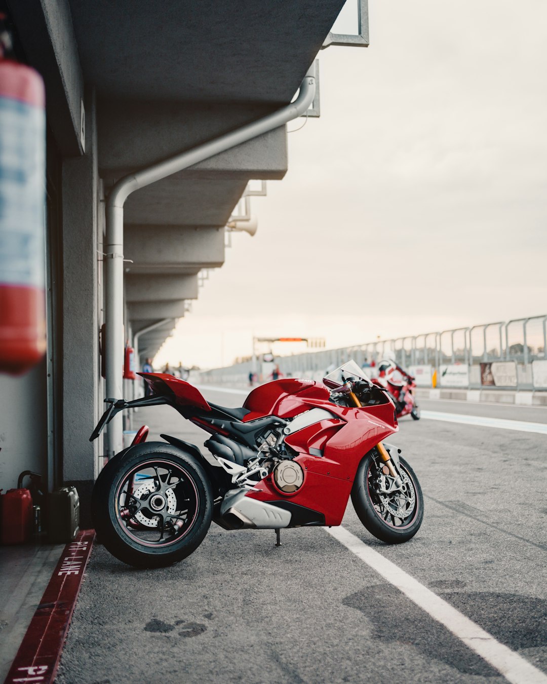 red sports bike parking near road during daytime