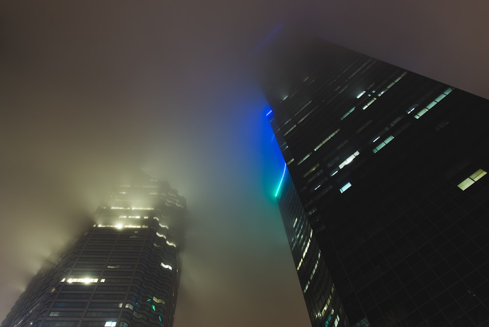 two tall buildings in a foggy city at night