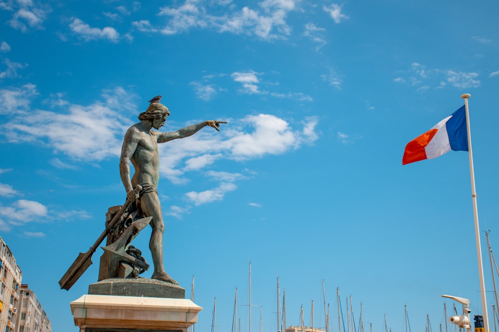 Estátua do homem nu perto da bandeira