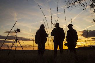 silhouette of 3 men standing besides camera