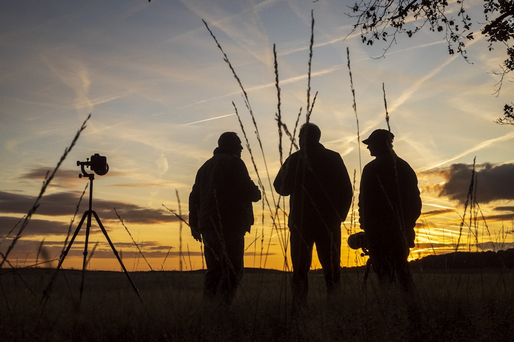 silhouette of 3 men standing besides camera