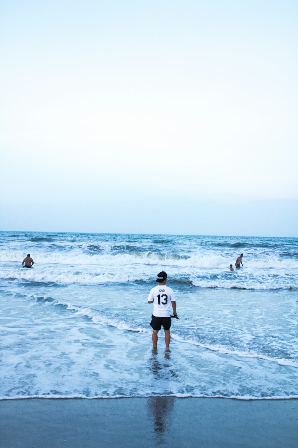man wearing white shirt standing on seashore