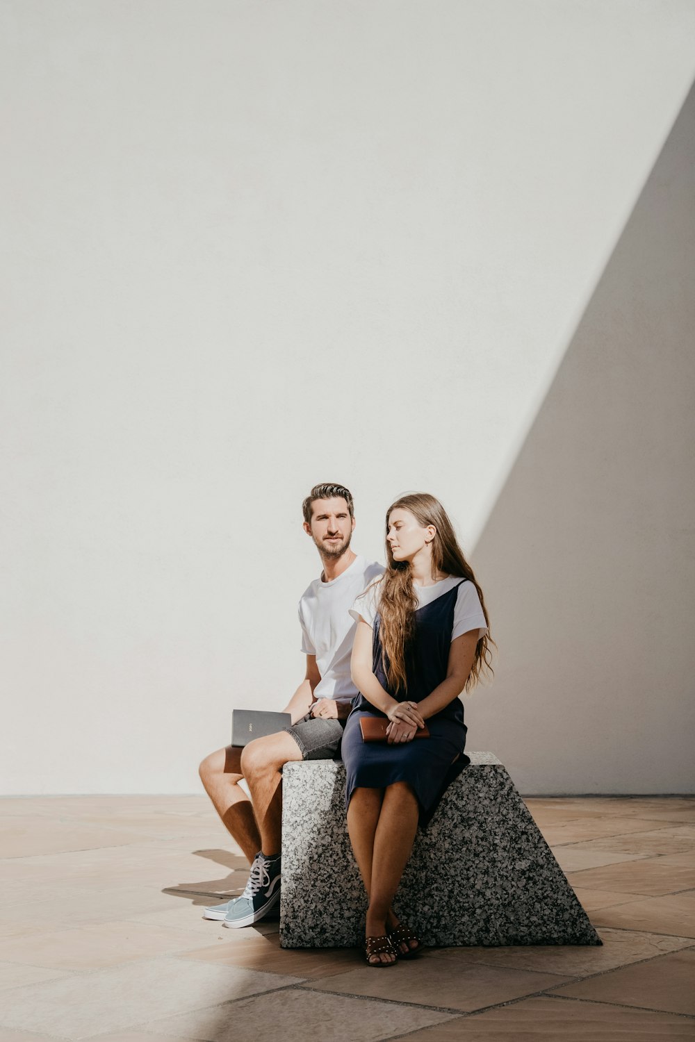 man and woman sitting on grey surface