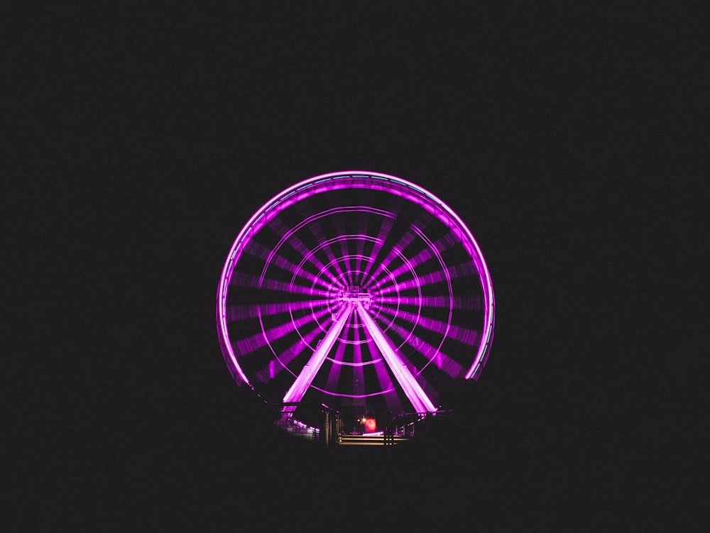Grande roue avec des lumières violettes pendant la nuit