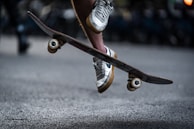 Close-up of professional skate shoes gripping the board mid-air during a trick.