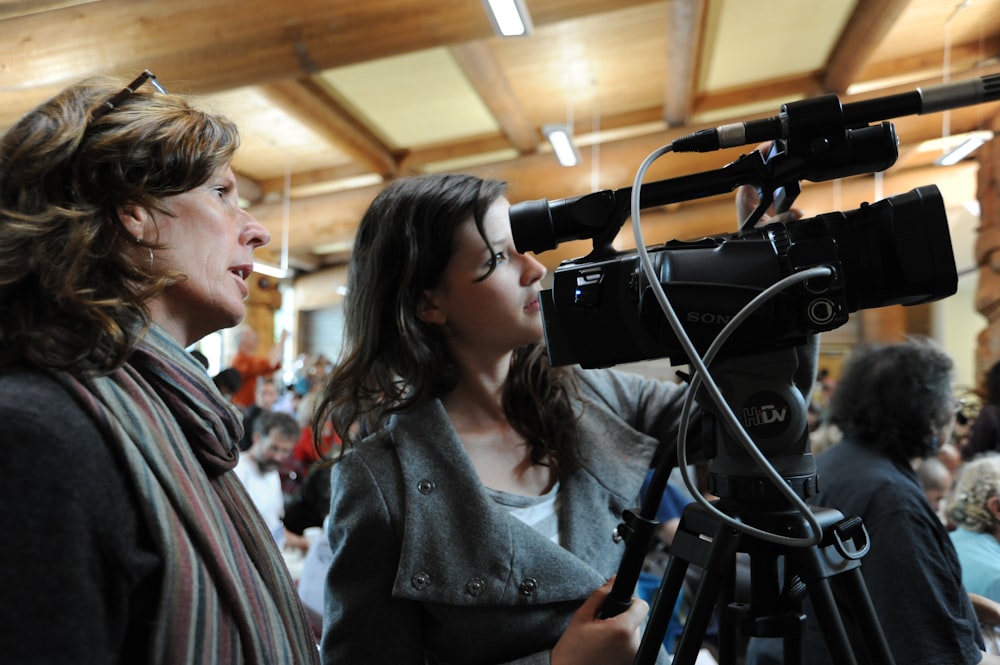 two women standing beside camera