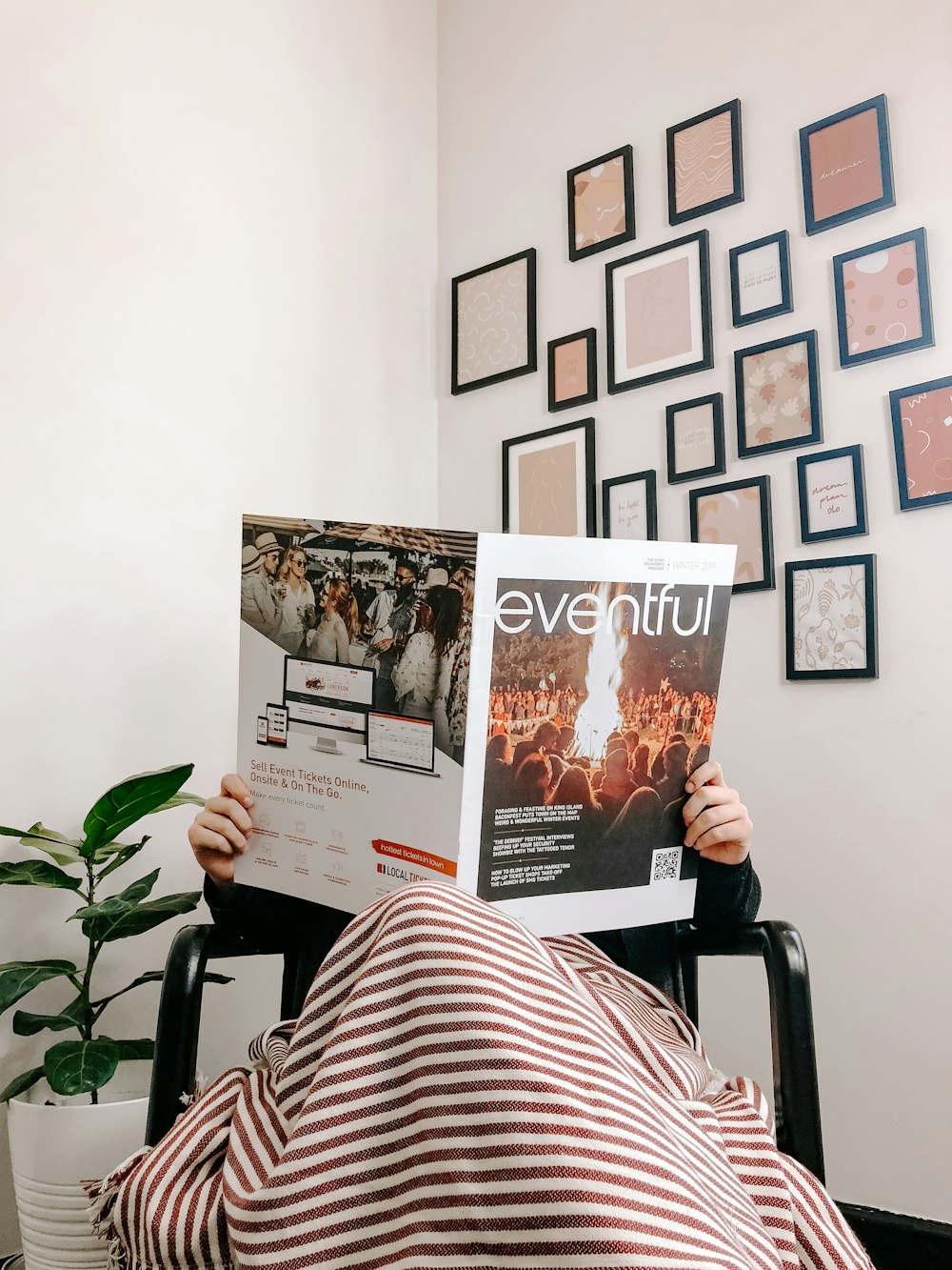 personne assise sur un fauteuil en train de lire un magazine