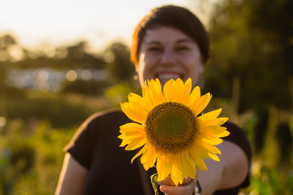 shallow focus photography unknown person holding yellow sunflower