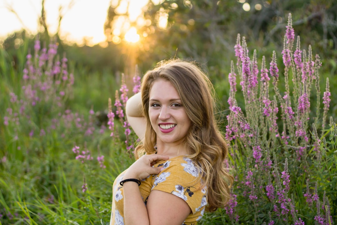 woman poses near pink petaled flowers