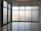 Large floor-to-ceiling glass windows are framed in dark metal, creating a modern and minimalistic design. The frosted glass provides a blurred view of the outside, allowing softened light to filter into the room. The floor is polished and reflects the light softly, adding to the clean and uncluttered aesthetic.