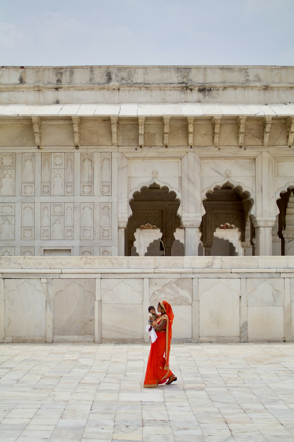 woman wearing red dress carrying baby outside