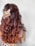 A person with long wavy brown hair viewed from the back, adorned with a decorative beaded hair accessory. The attire features a colorful and intricate pattern.