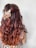 A person with long wavy brown hair viewed from the back, adorned with a decorative beaded hair accessory. The attire features a colorful and intricate pattern.