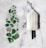 A white ice cream popsicle with a black stick lies on a marble surface next to various pieces of green and clear sea glass arranged in a gallery-like display.