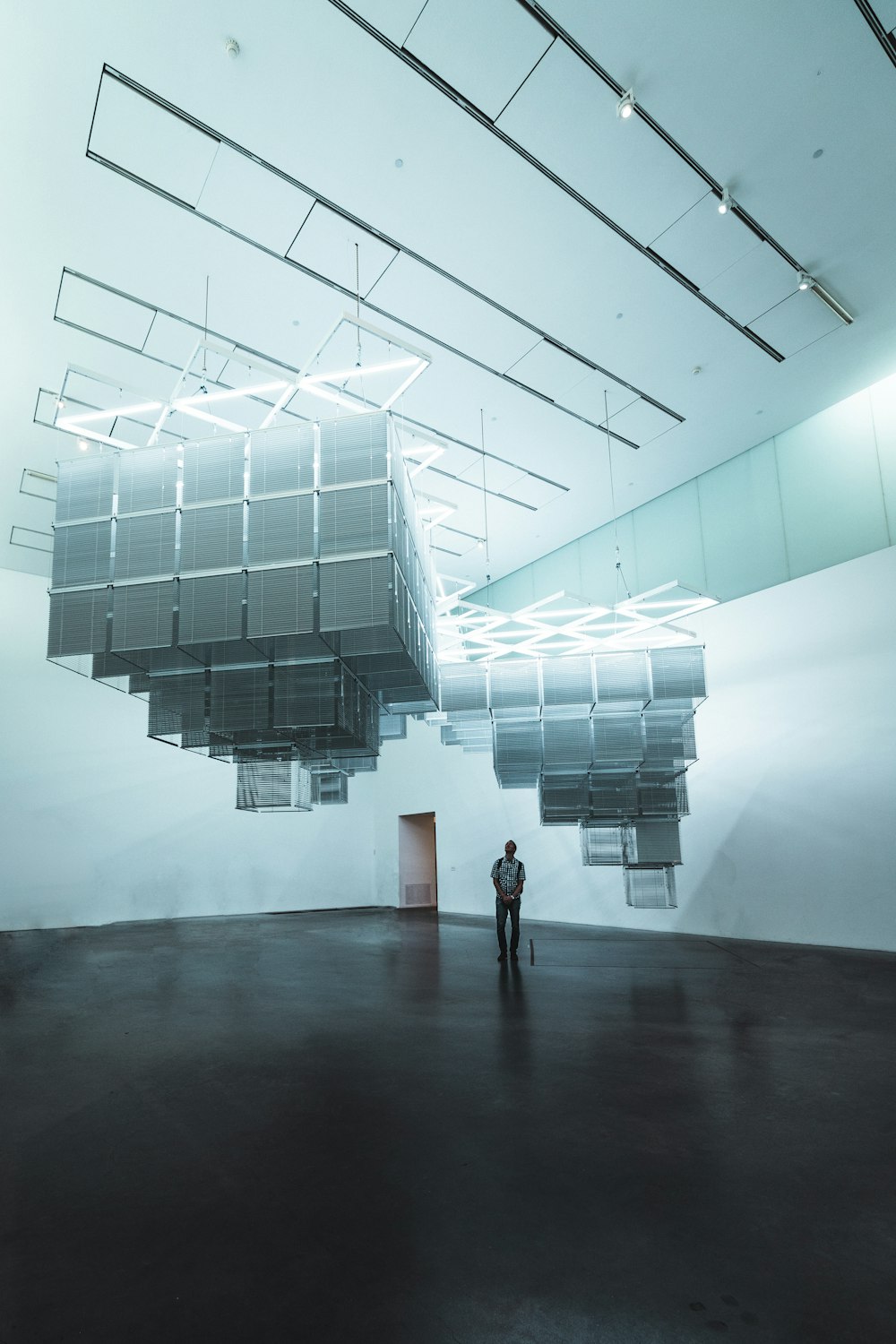 man standing under layered box chandelier